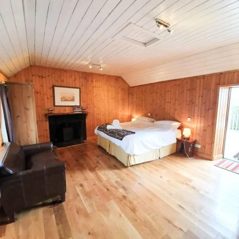 a bedroom with a bed and a couch and a fireplace at The Bothy in Lumphanan