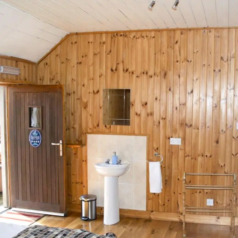 a bathroom with a sink in a wooden wall at The Bothy in Lumphanan