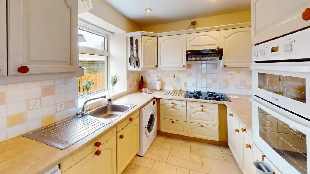 a kitchen with white cabinets and a sink at Birchview in Aviemore