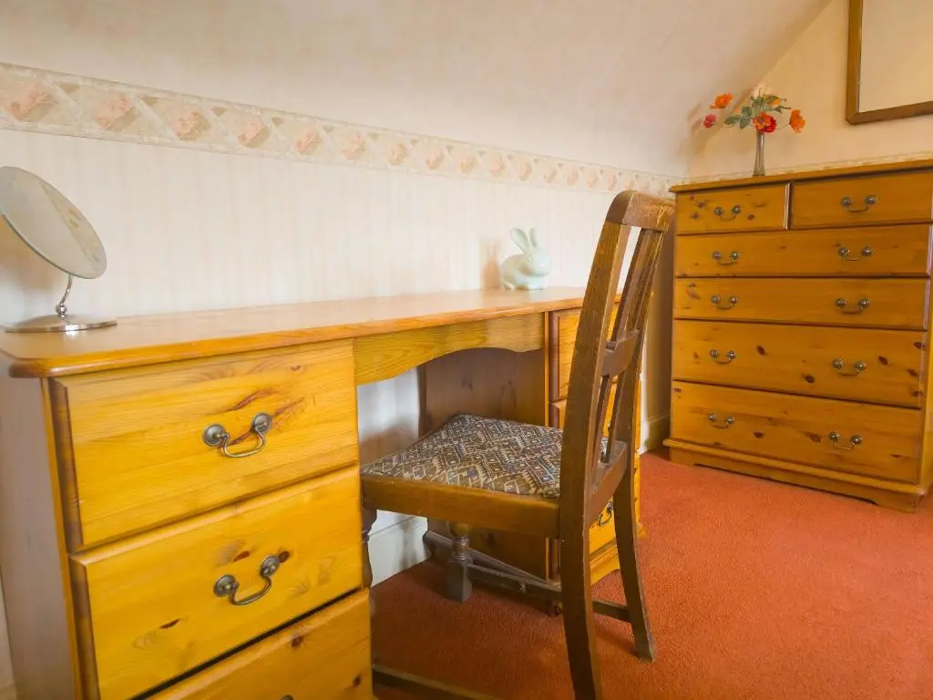 a wooden desk with a chair next to a dresser at Birchview in Aviemore