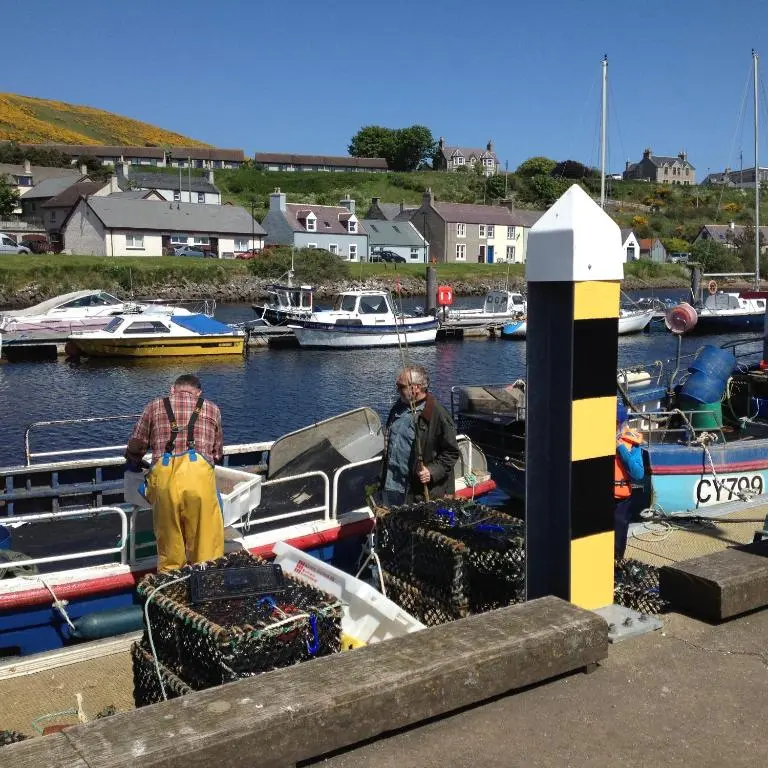 two men standing on a boat in a harbor at The Hoose in Helmsdale