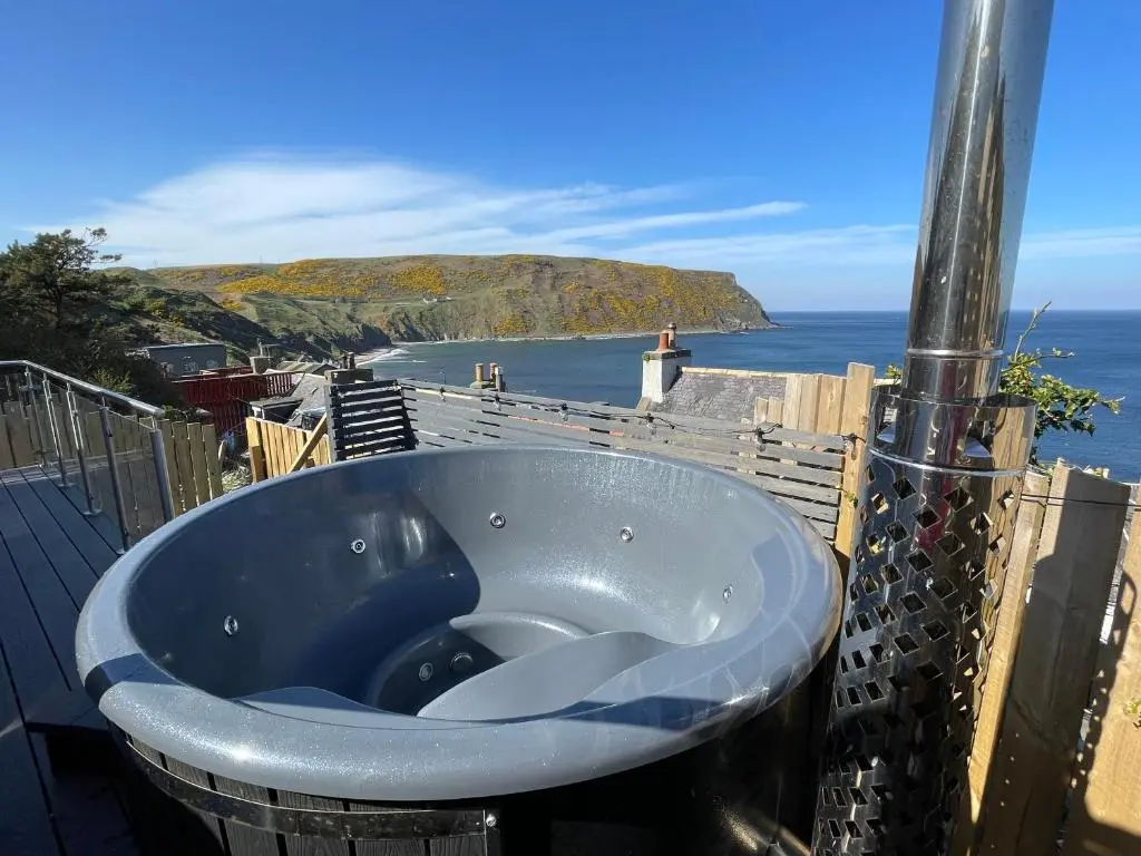 a bath tub with a view of the ocean at Gamrie Beach Bothy in Gardenstown
