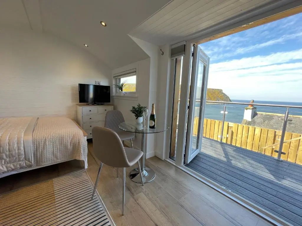 a bedroom with a bed and a view of the ocean at Gamrie Beach Bothy in Gardenstown