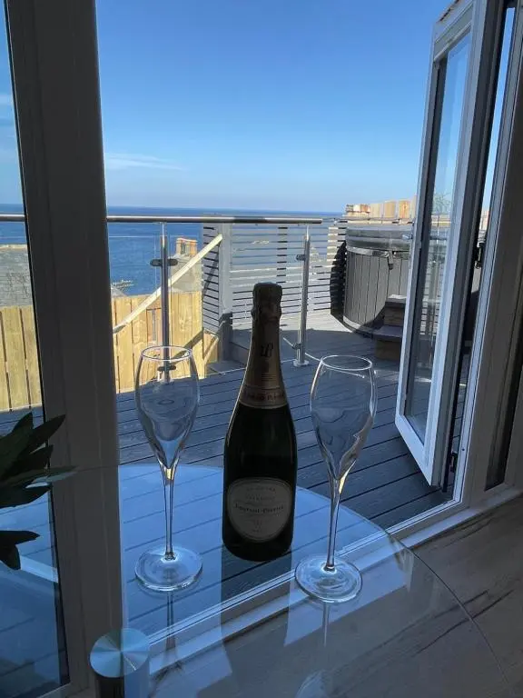 a bottle of wine and two glasses on a table on a balcony at Gamrie Beach Bothy in Gardenstown