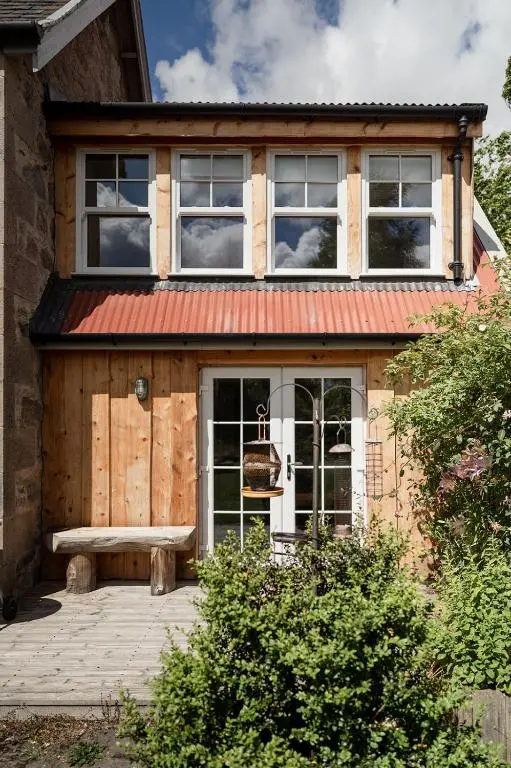 a house with a bench in front of it at Broomfeild Bothy Comes with a Sauna in Boat of Garten