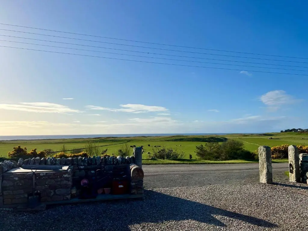 a building with a stone wall on the side of a road at Dalchalm Hideaway in Brora