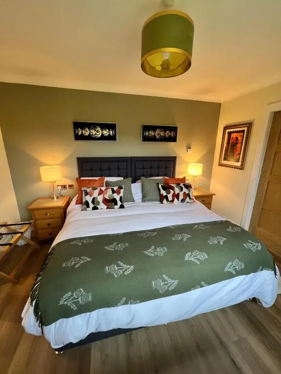 a bedroom with a large bed with a green comforter at Dalchalm Hideaway in Brora