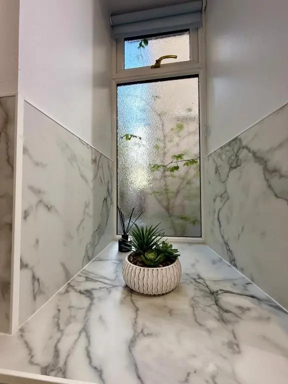 a bathroom with a window and a potted plant on a marble counter at Sea Breeze Cottage short walk to the beach, Nairn in Nairn