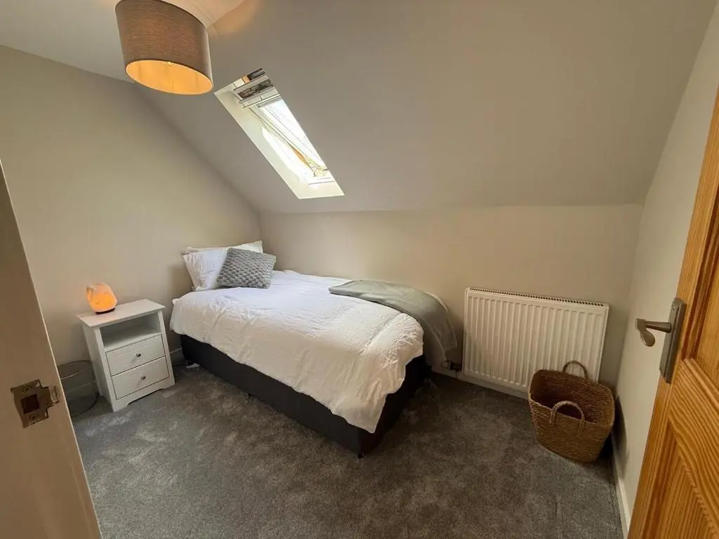 a small bedroom with a bed and a skylight at Sea Breeze Cottage short walk to the beach, Nairn in Nairn