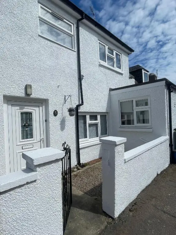 a white house with a gate and a door at Sea Breeze Cottage short walk to the beach, Nairn in Nairn