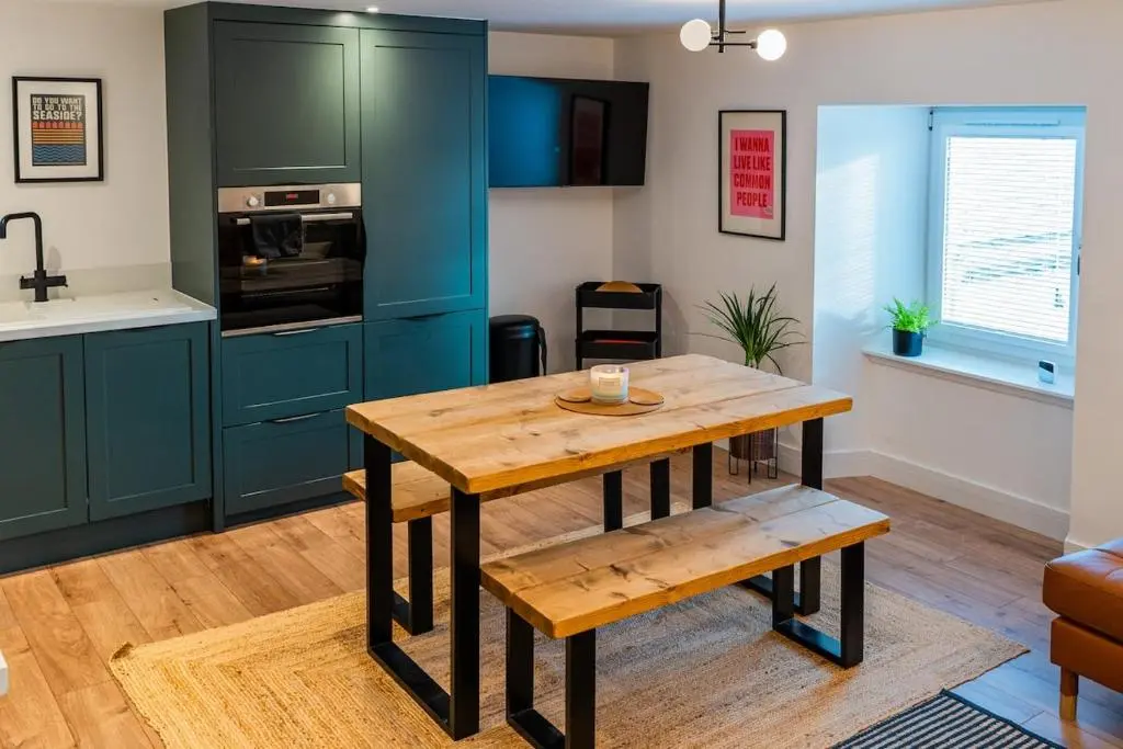 a kitchen with blue cabinets and a wooden table at The Lookout, Lossiemouth in Lossiemouth
