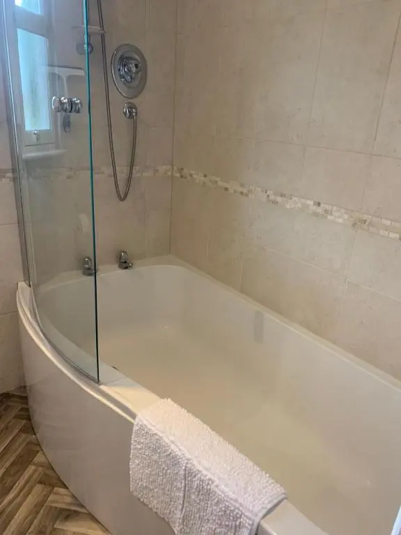 a bath tub with a shower with a glass door at Inchmarlo Villa 29 Banchory in Inchmarlo