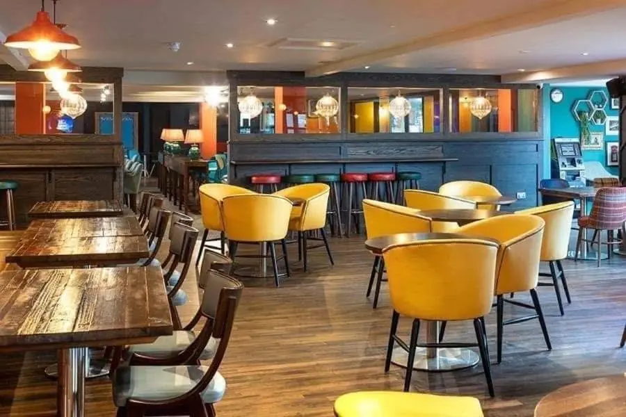 a restaurant with wooden tables and yellow chairs at 36 Lighthouse View in Lossiemouth