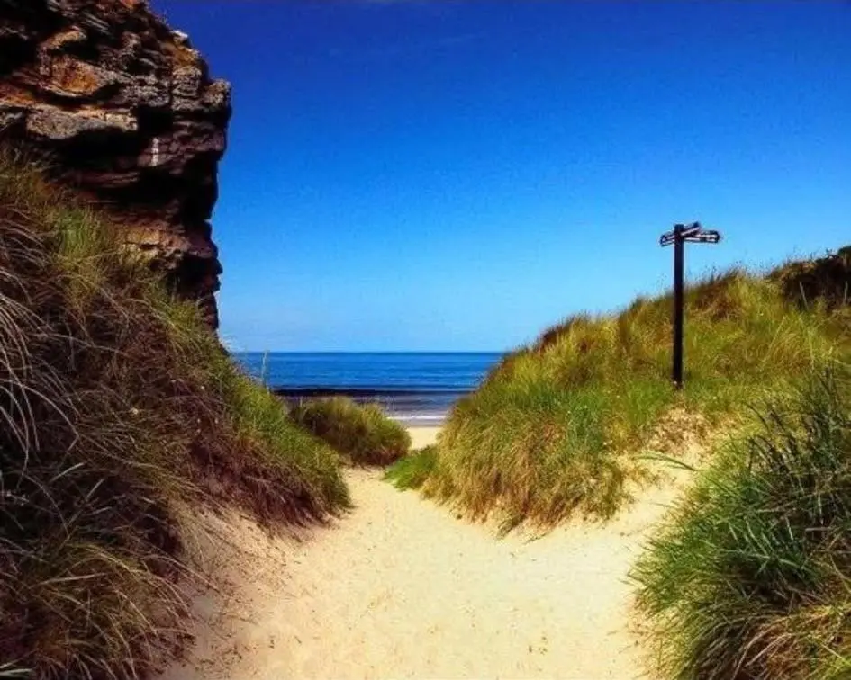 a dirt path leading to a beach with the ocean at 36 Lighthouse View in Lossiemouth