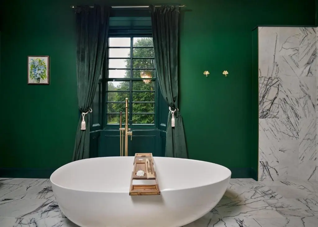 a white tub in a green bathroom with a window at Old Manse of Craggan in Glenlivet