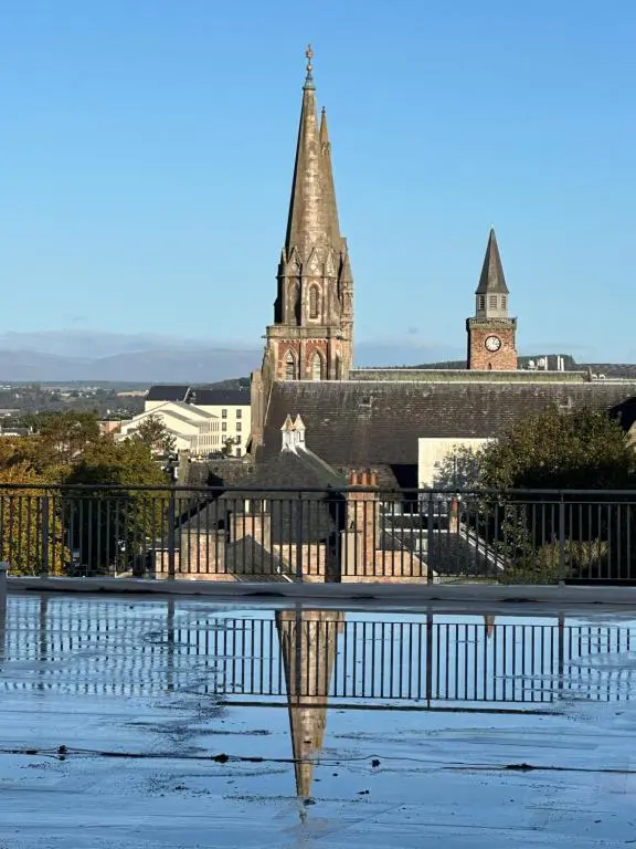 an old building with a clock tower and a church at St\u0101 by The Bridge, Inverness City Centre in Inverness