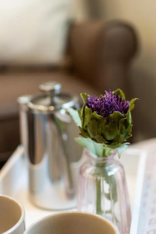 a glass vase with a purple flower in it on a table at Bridgend Bothy in Drumnadrochit