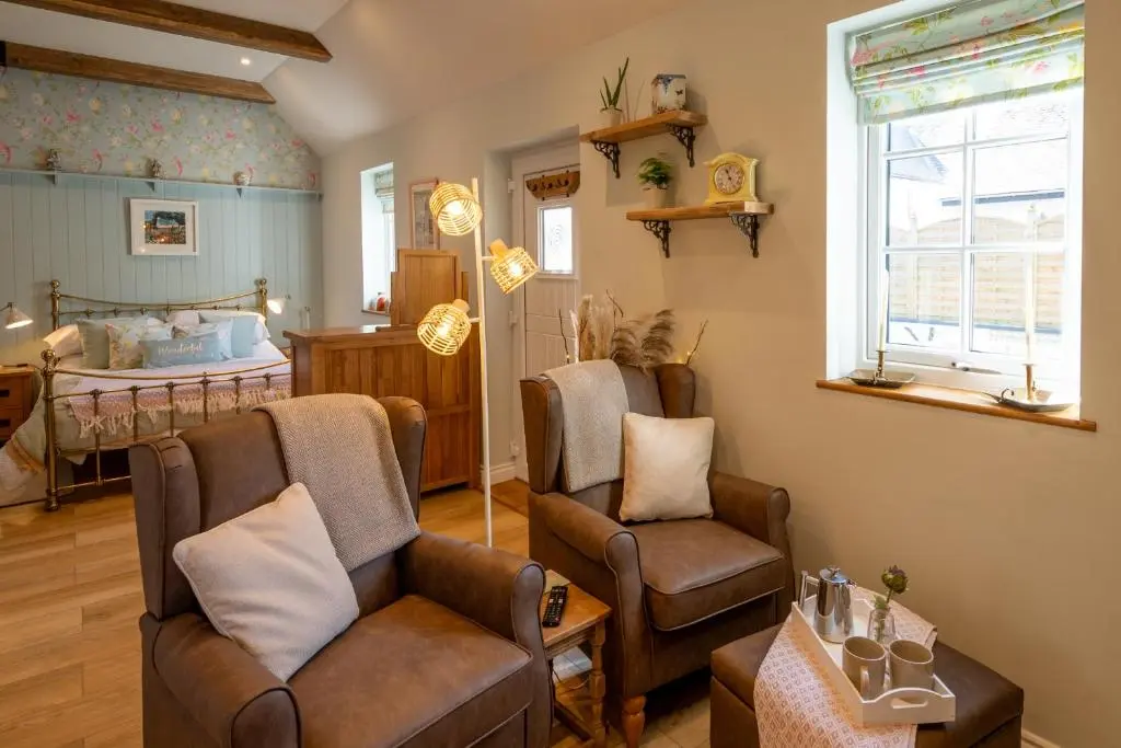 a living room with a couch and chairs and a bed at Bridgend Bothy in Drumnadrochit