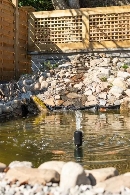 a pool of water in a garden with rocks at Bridgend Bothy in Drumnadrochit