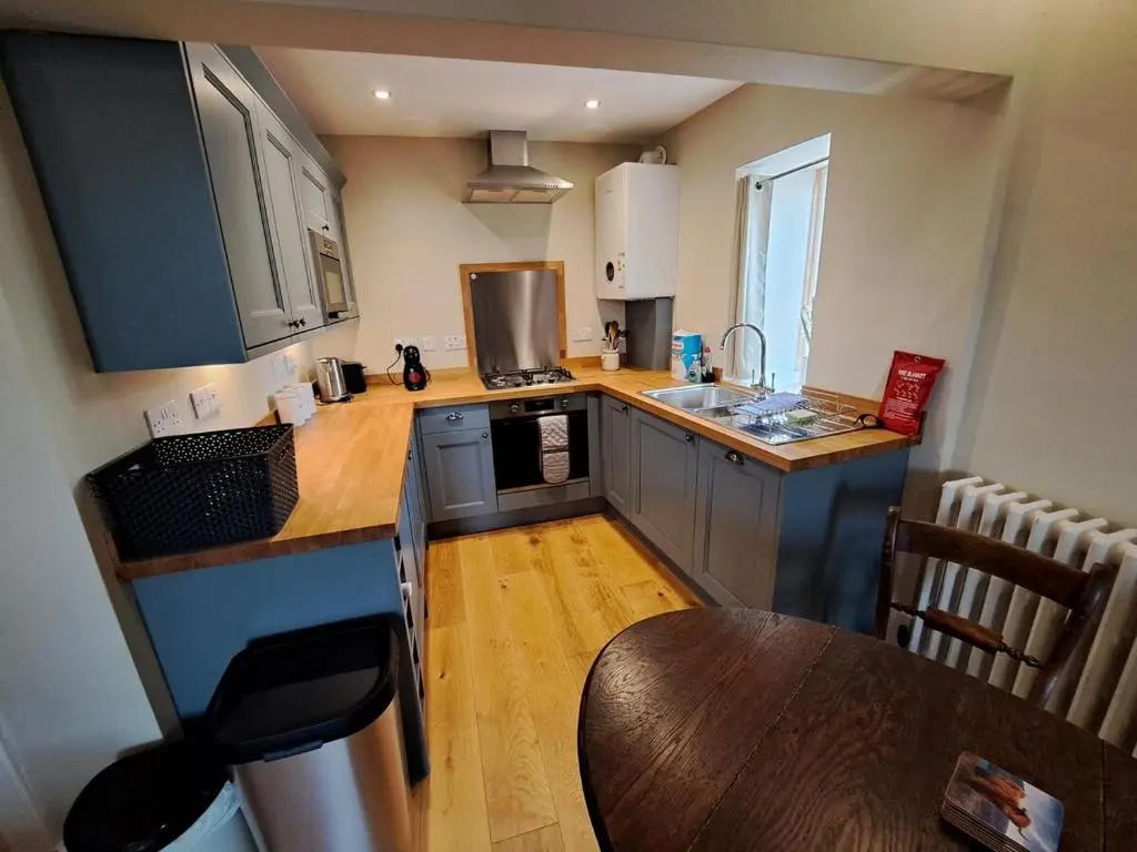 a small kitchen with a wooden floor and a table at Cosy Riverside Apartment with free parking in Inverness