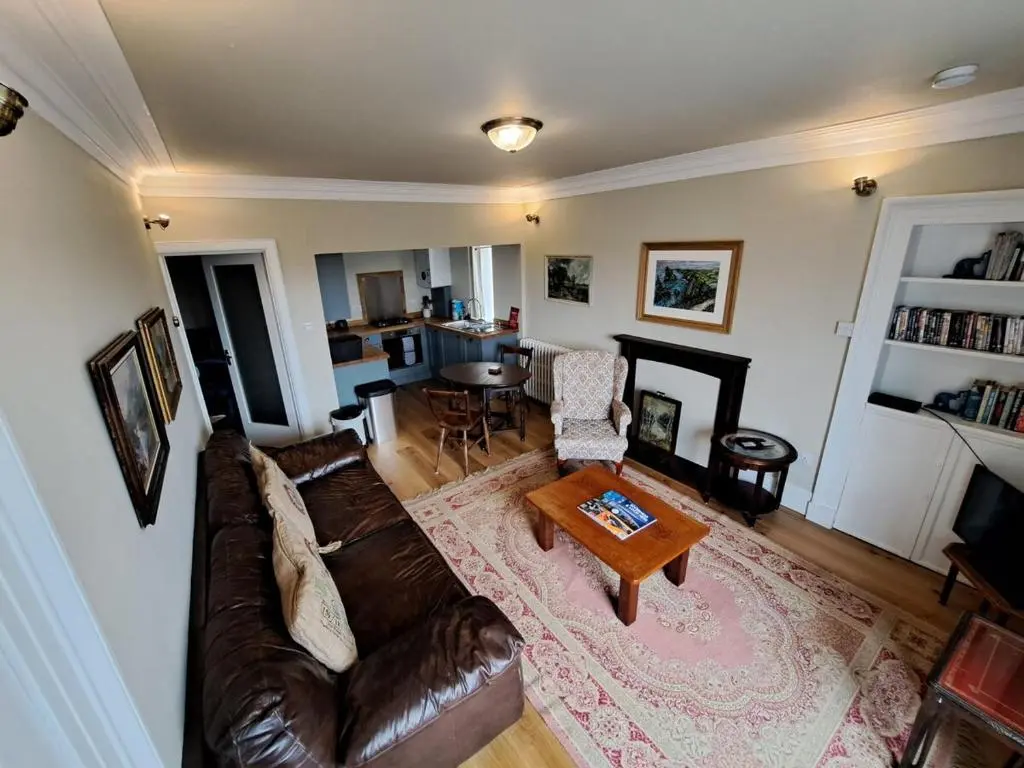 a living room with a brown leather couch and a table at Cosy Riverside Apartment with free parking in Inverness