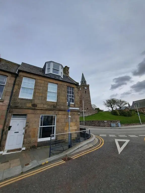 an old brick building with a clock tower on top at Cosy Riverside Apartment with free parking in Inverness