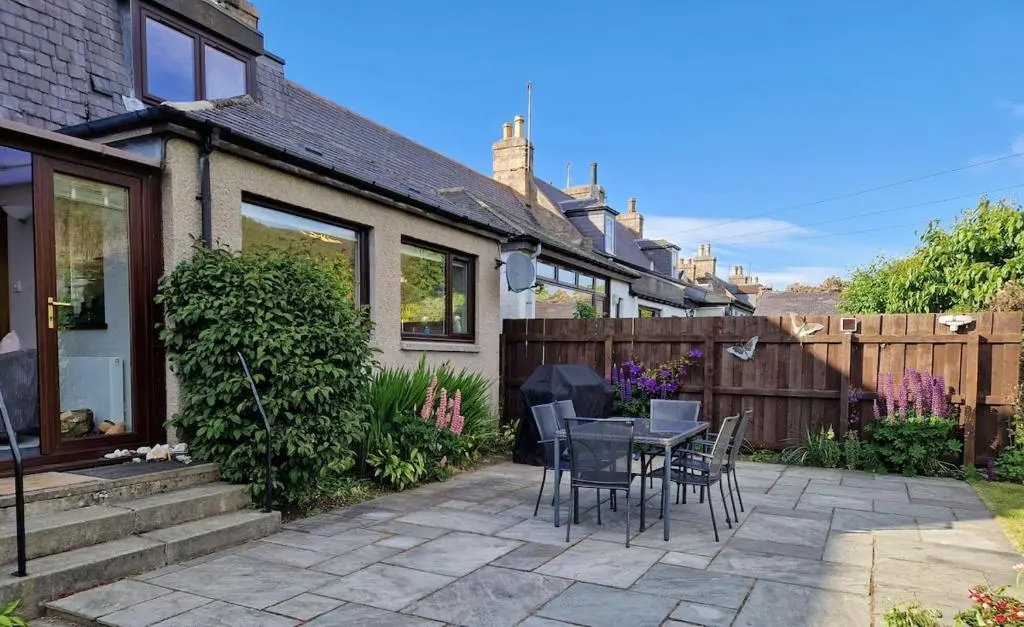 a patio with a table and chairs in front of a house at Spacious cosy welcoming cottage in Ballater