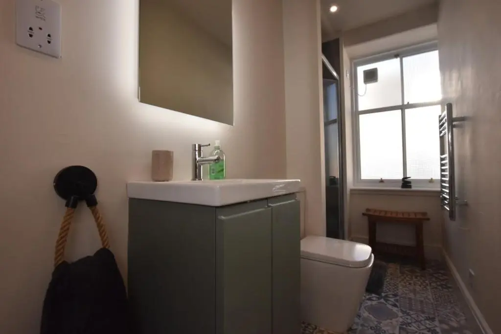 a bathroom with a sink and a toilet and a window at The MacKenzie Apartment in Beauly