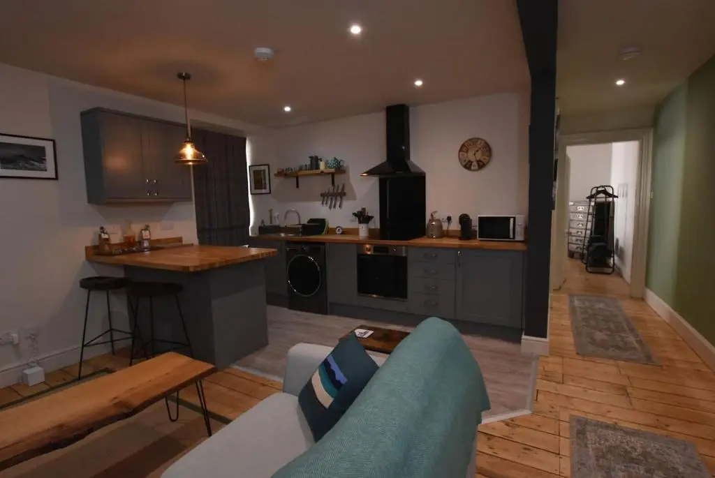 a living room with a couch and a kitchen at The MacKenzie Apartment in Beauly