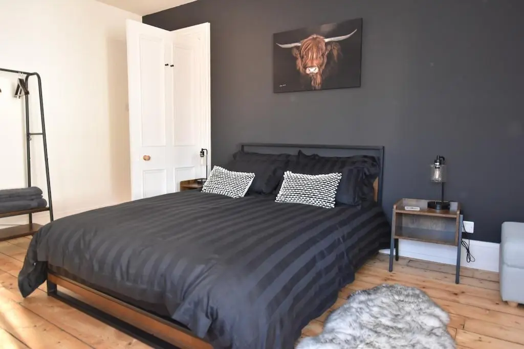 a bedroom with a bed with a bull picture on the wall at The MacKenzie Apartment in Beauly