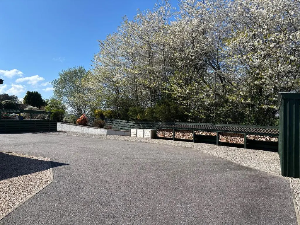 an empty parking lot with a fence and trees at Danian B&B in Dingwall