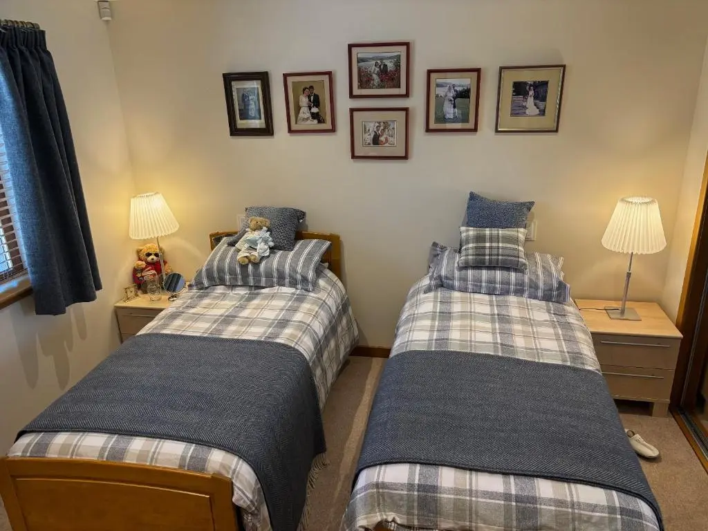 two twin beds in a bedroom with pictures on the wall at Danian B&B in Dingwall