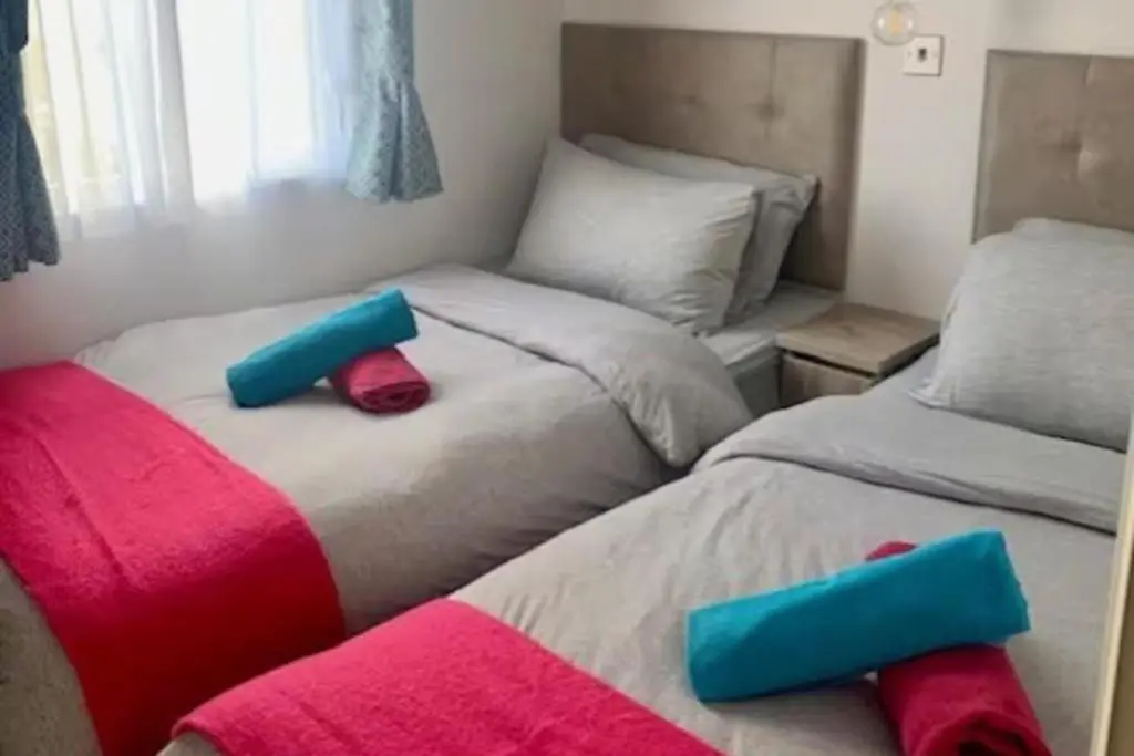 two beds in a bedroom with blue and pink pillows at Findhorn Lodge - Peaceful - Pets - Sleeps 4 in Forres