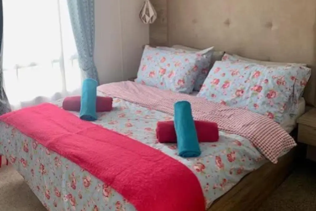 a bedroom with a bed with a pink blanket and pillows at Findhorn Lodge - Peaceful - Pets - Sleeps 4 in Forres