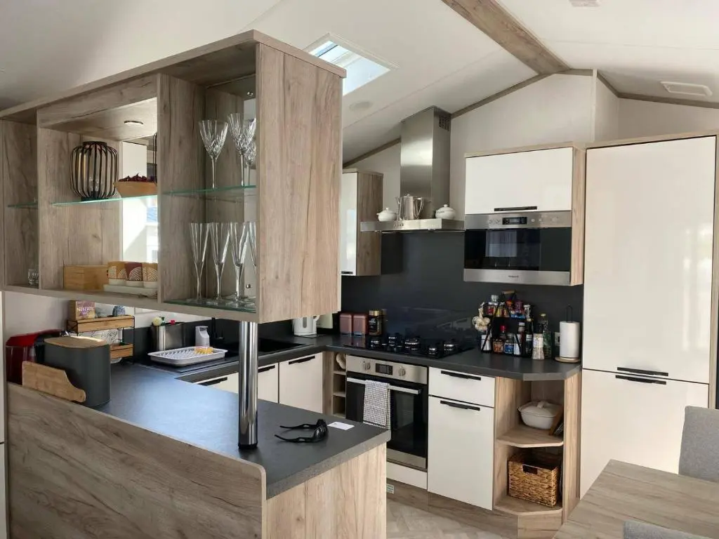 a kitchen with white cabinets and black counter tops at Findhorn Lodge - Peaceful - Pets - Sleeps 4 in Forres