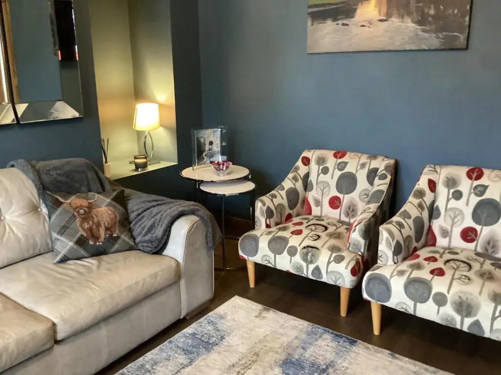 a living room with a couch and two chairs at Charlies in Huntly