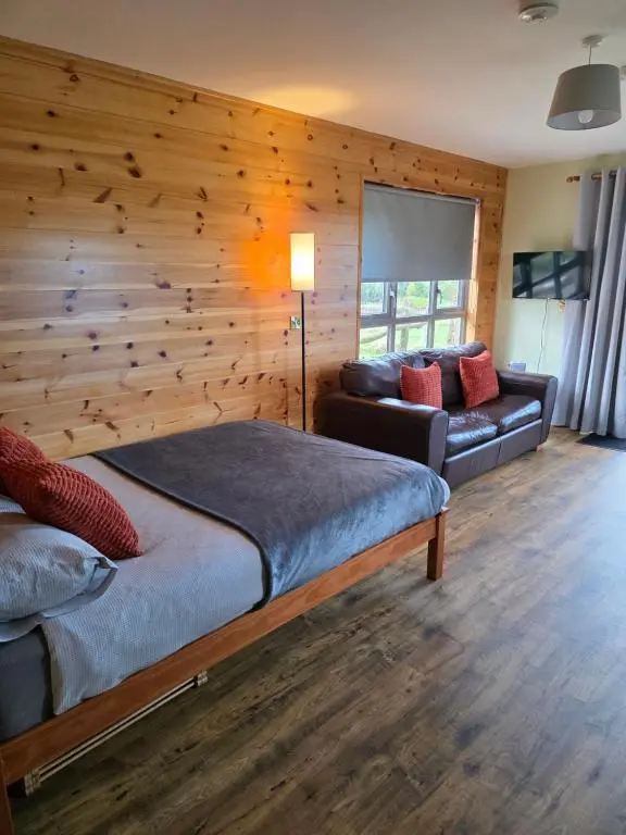 a bedroom with a wooden wall with a bed and a couch at Cabin View in Cuminestown