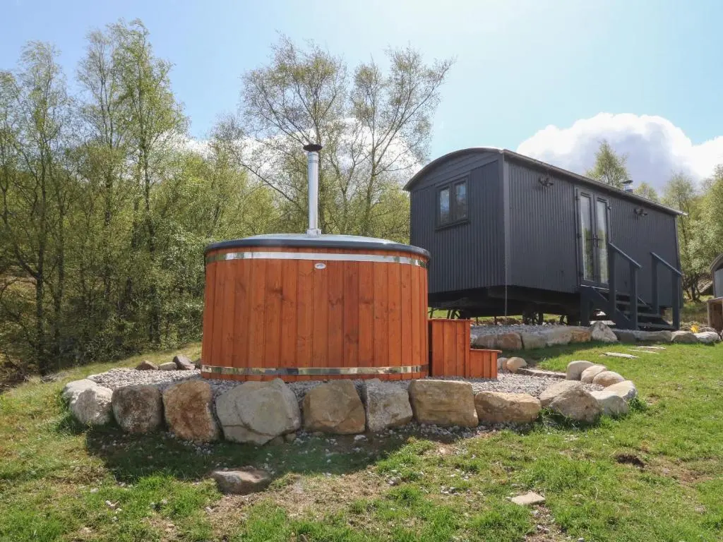 a house with a large wooden tub in front of it at Coraldie in Newtonmore