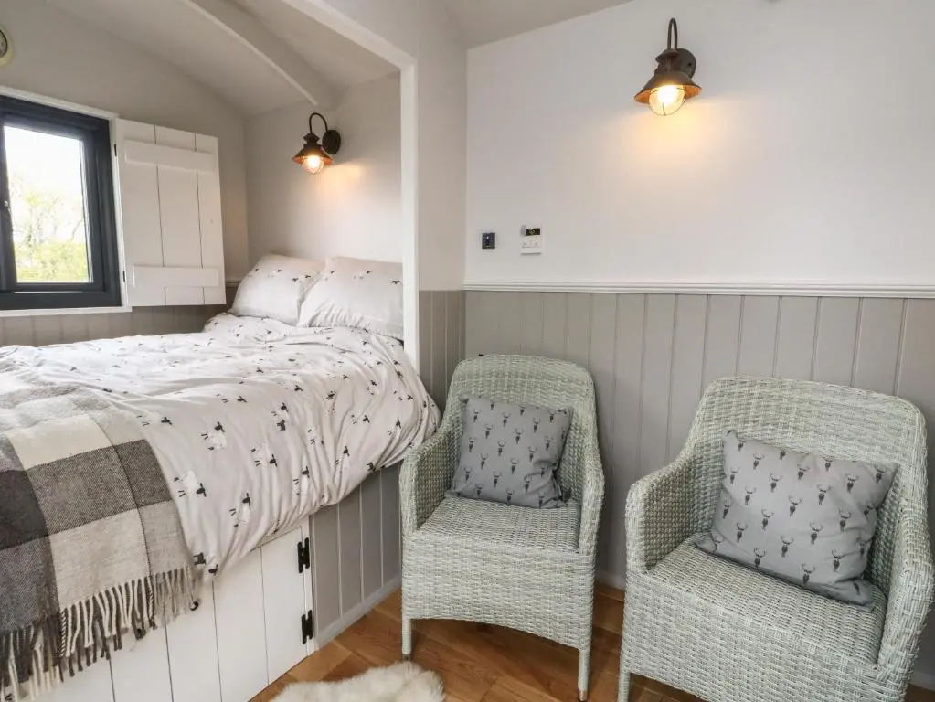 a bedroom with a bed and two chairs at Coraldie in Newtonmore