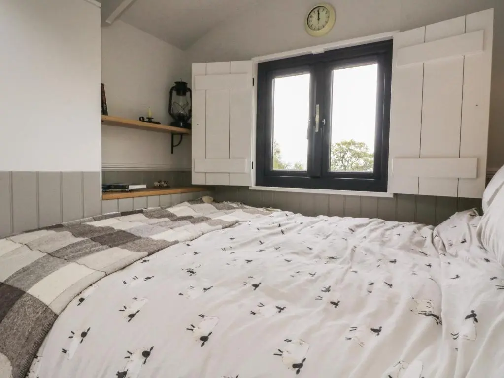 a bedroom with a large bed with a clock on a window at Coraldie in Newtonmore