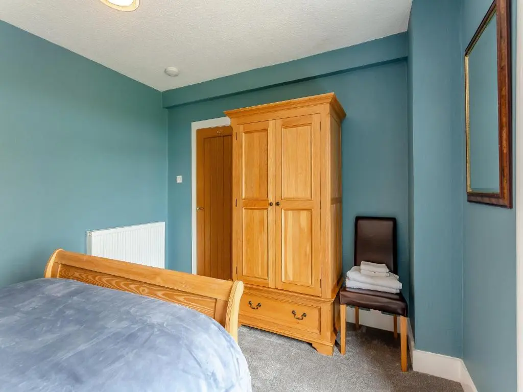 a bedroom with blue walls and a wooden cabinet at Hogholm Farmhouse in Inverurie