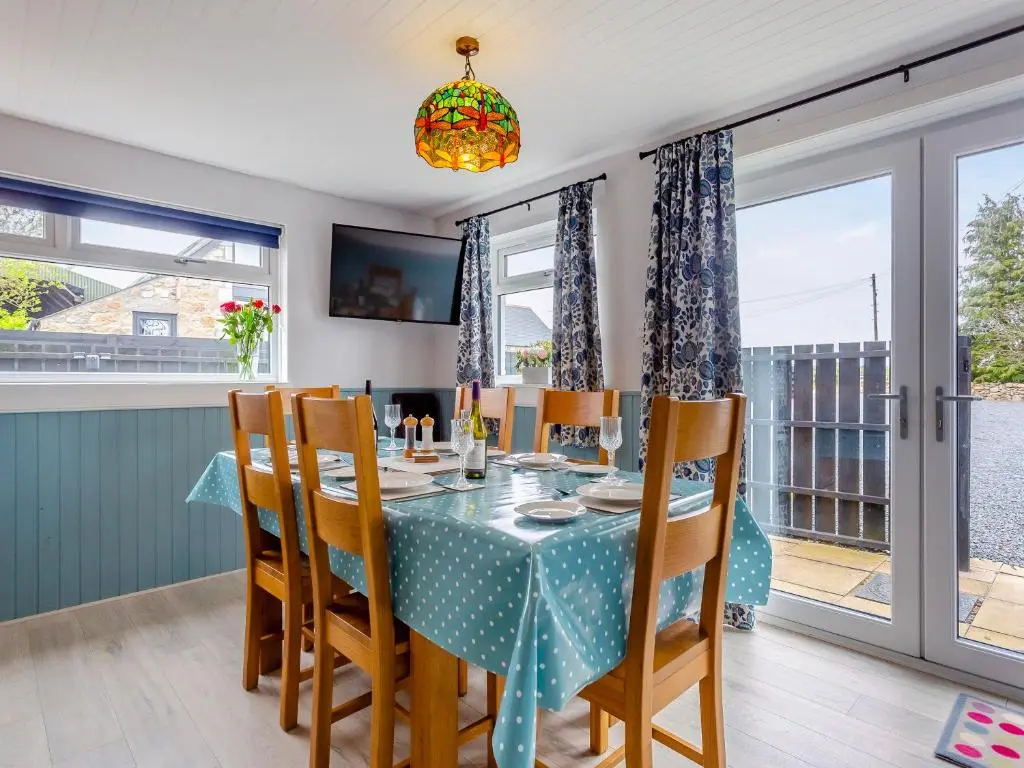 a dining room with a table and chairs and windows at Hogholm Farmhouse in Inverurie