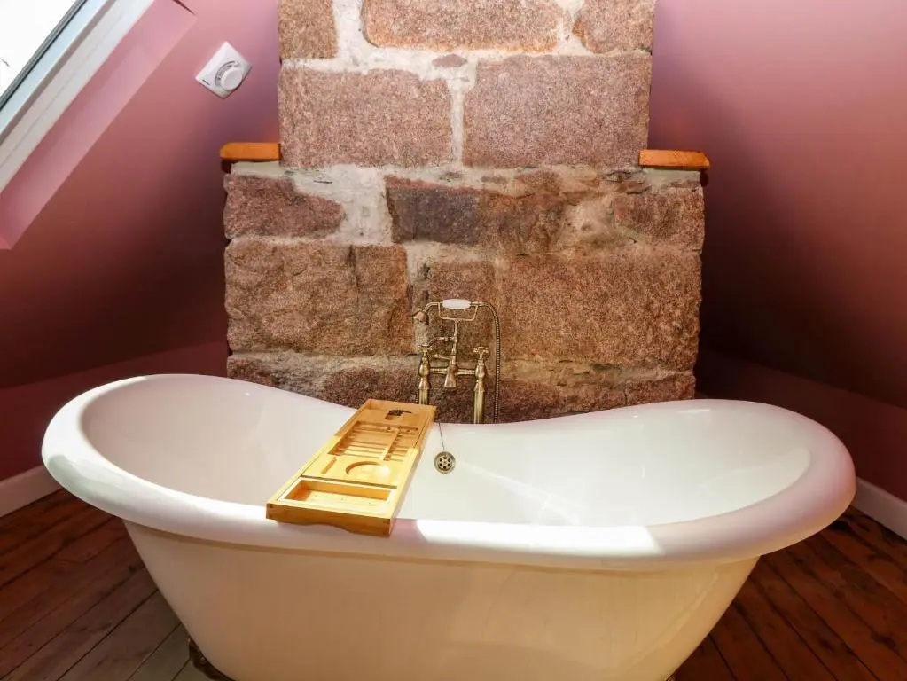 a bath tub in a bathroom with a brick wall at Evansford in Ballater