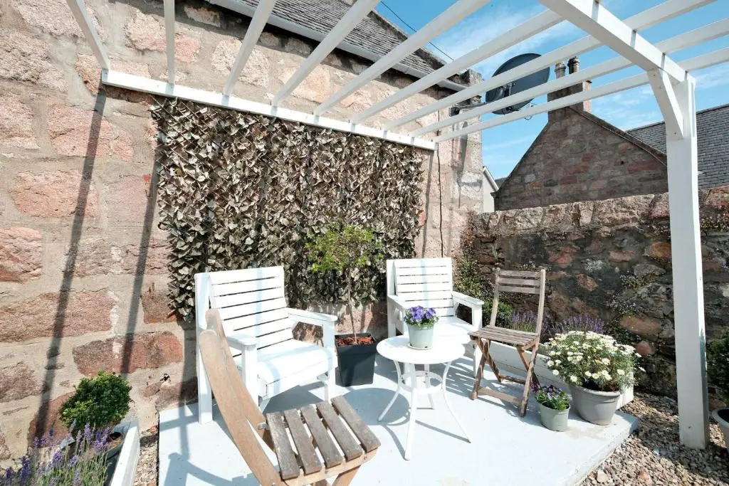 two white chairs and a table on a patio at Craigen Cottage Ballater in Ballater