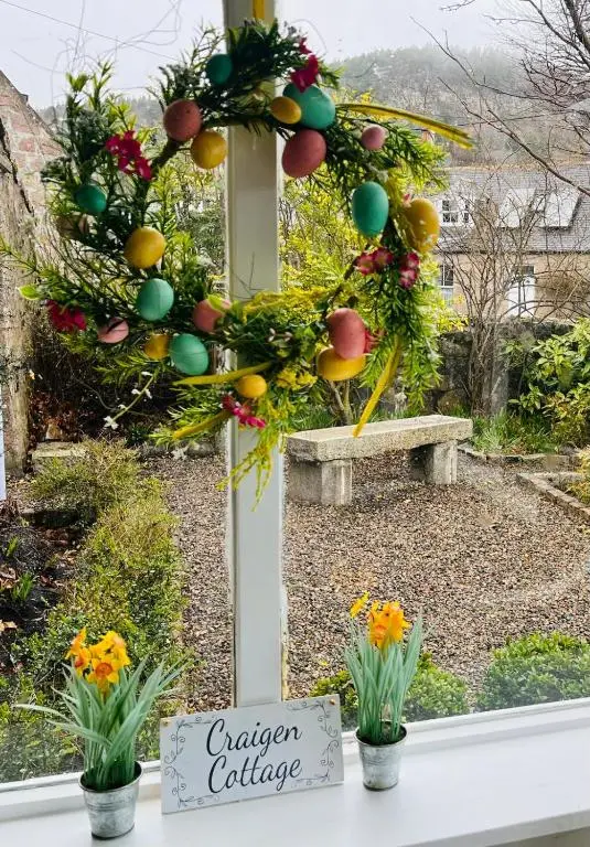 a christmas wreath on a window with a garden collective sign at Craigen Cottage Ballater in Ballater