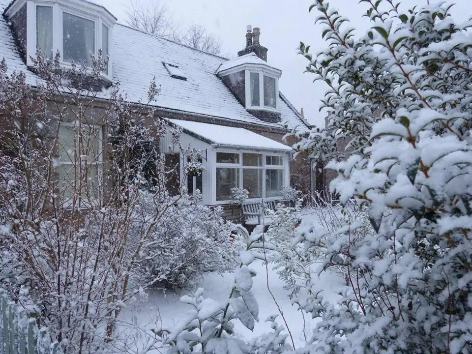 a house covered in snow in front of a yard at Craigen Cottage Ballater in Ballater
