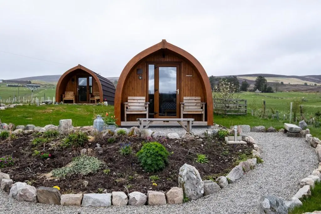 a wooden cabin in a field with a garden at Luxury Pod 3 in Bonar Bridge