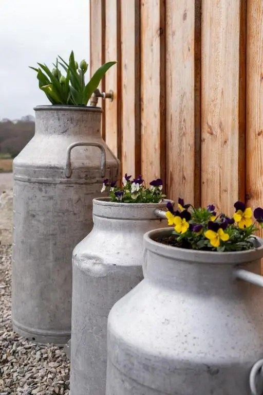 two cement vases with flowers in them next to a fence at Luxury Pod 3 in Bonar Bridge