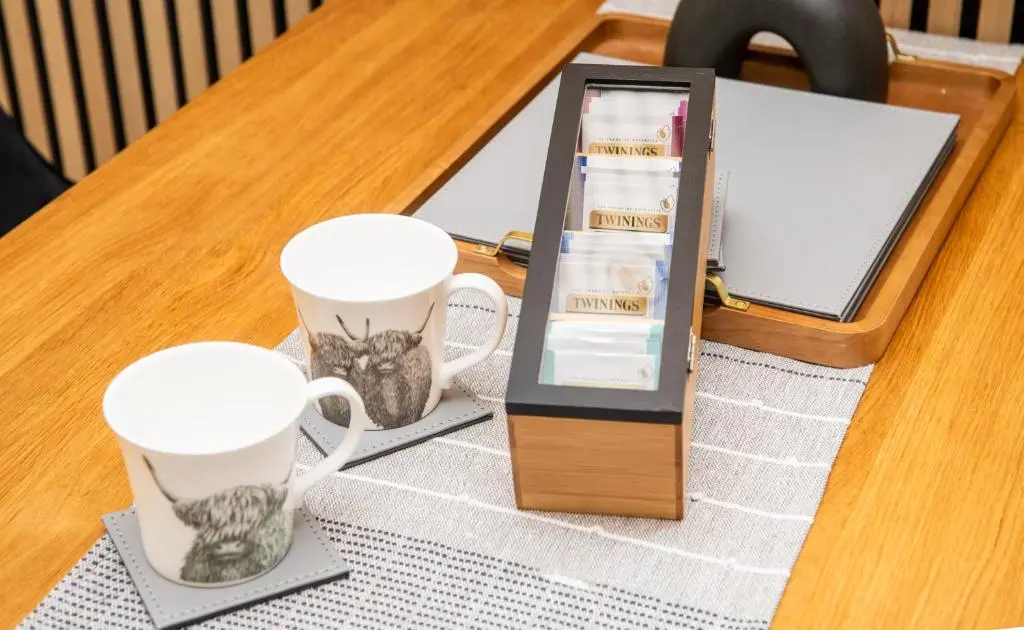 two coffee cups and a tablet on a table at Highland Cow Apartment in Inverness