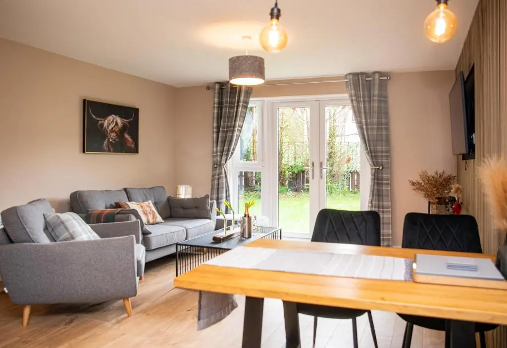 a living room with a table and a couch at Highland Cow Apartment in Inverness